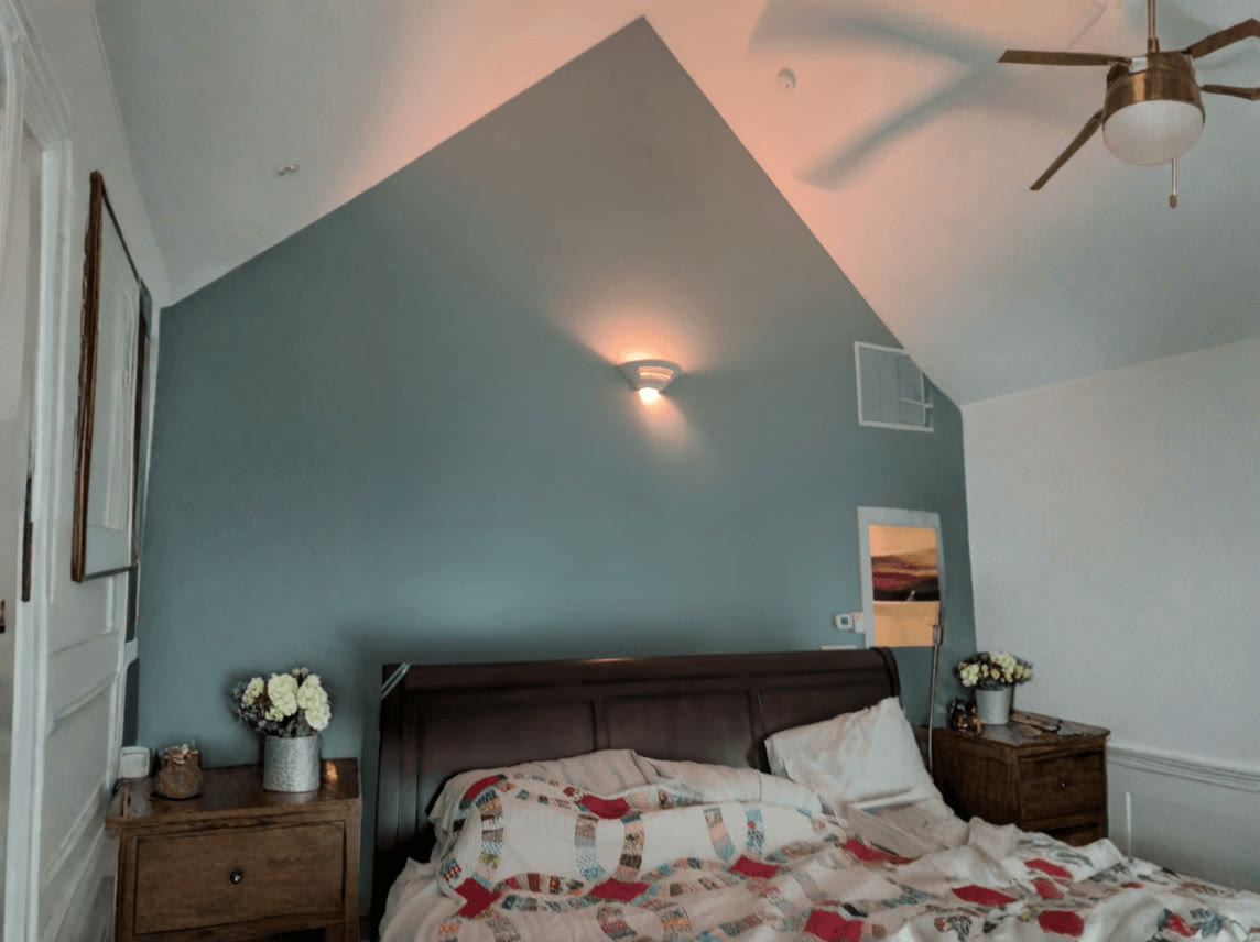 Bedroom with a freshly painted teal accent wall up to the vaulted ceiling
