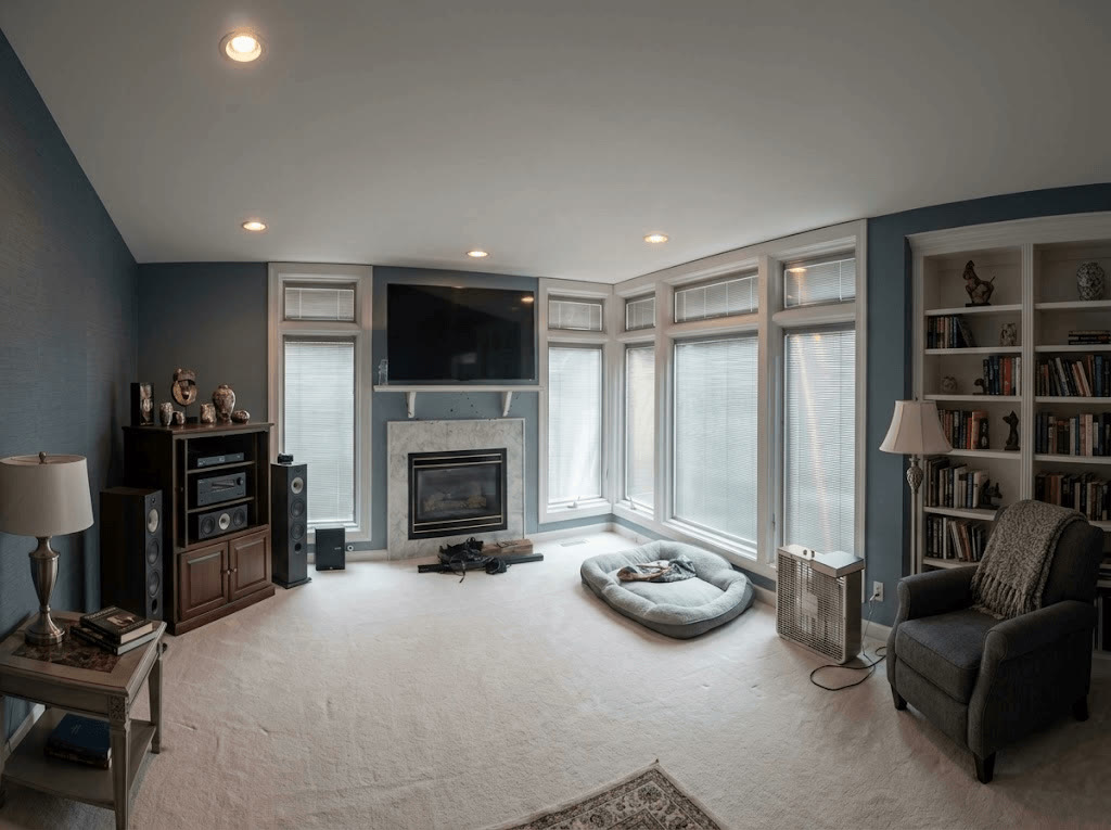 Living room with deep blue accent walls, fireplace, tall windows, and built-in bookshelves